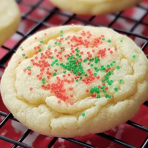 Close-up of a festive, easy sugar cookie with red and green sprinkles on a cooling rack.