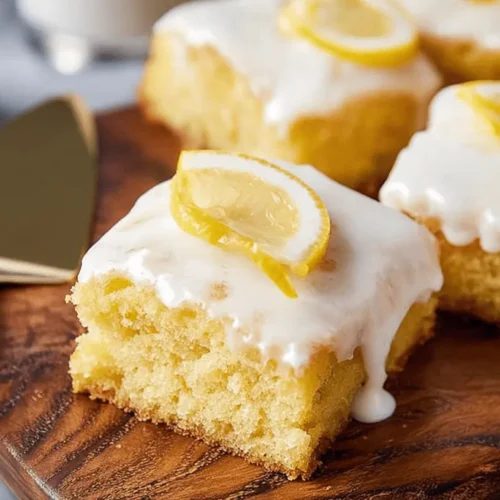 Delicious squares of moist lemon cake with white glaze and fresh lemon slices on a rustic wooden board, perfect for inspiring lemon cake mix recipes.