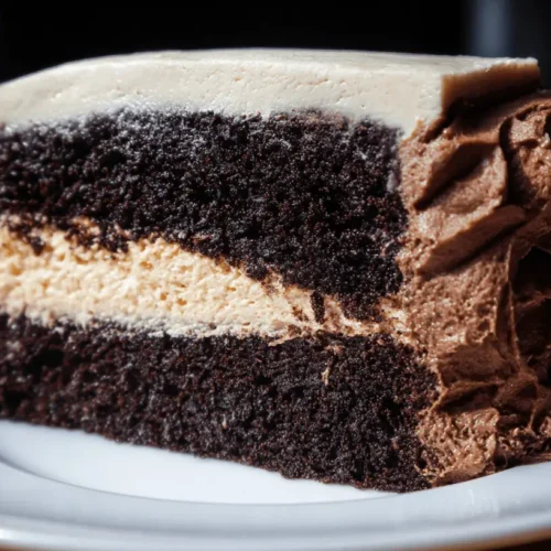 Decadent slice of multi-layered dark chocolate vegan cake with creamy filling and textured frosting.