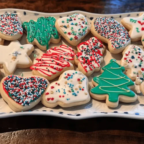 An elegant oblong platter holds a delightful assortment of homemade Christmas cookies, decorated with festive royal icing and colorful sprinkles.