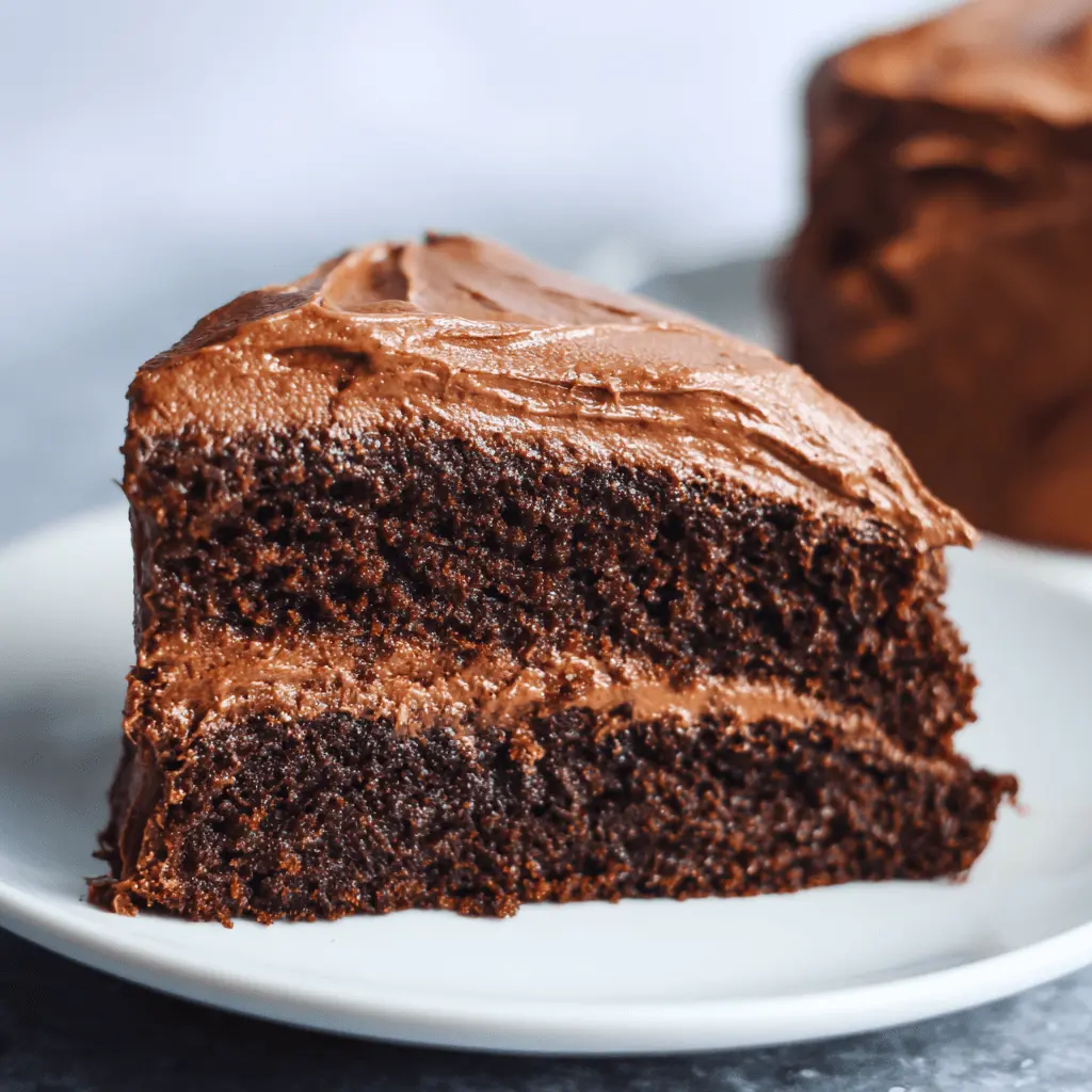 Close-up of a decadent slice of chocolate cake showcasing rich chocolate cake frosting between moist layers and on top.
