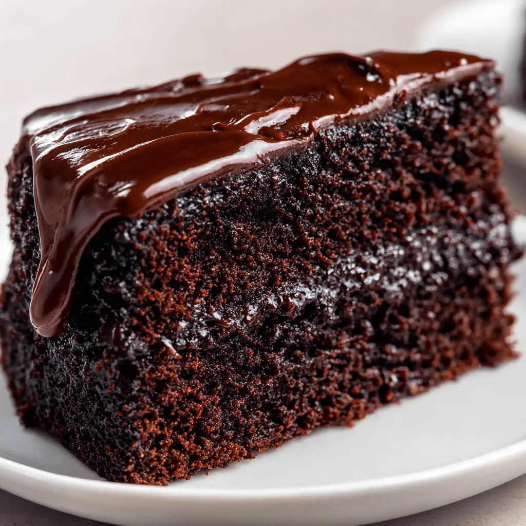A close-up of a decadent slice of moist Hersheys chocolate cake with rich, glossy ganache dripping down its side, presented on a white plate.